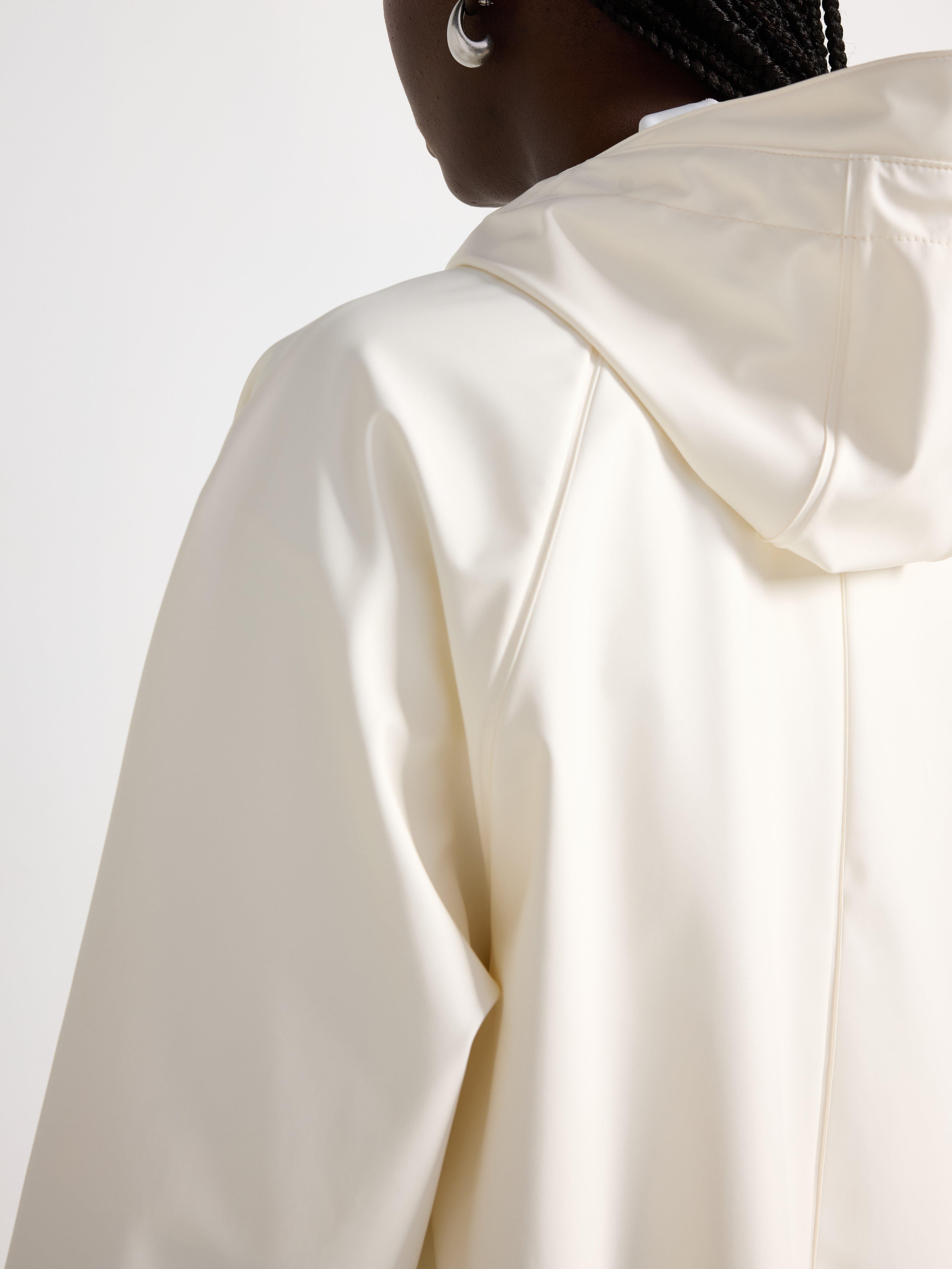 Chaqueta impermeable con capucha color blanco roto.