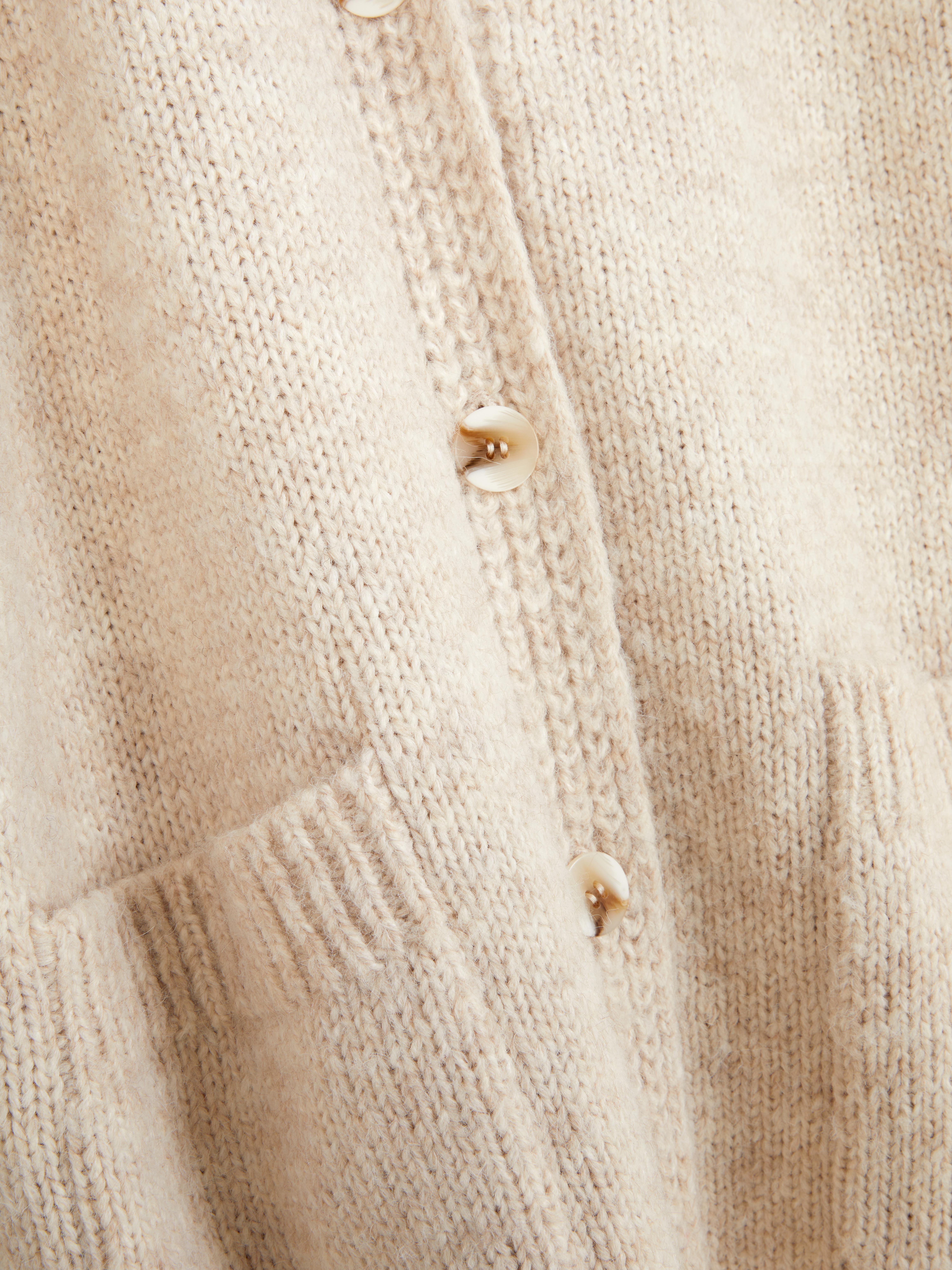 Oversize-Strickjacke. Eine lange Strickjacke mit Oversize-Schnitt, V-Ausschnitt und aufgesetzten Taschen.