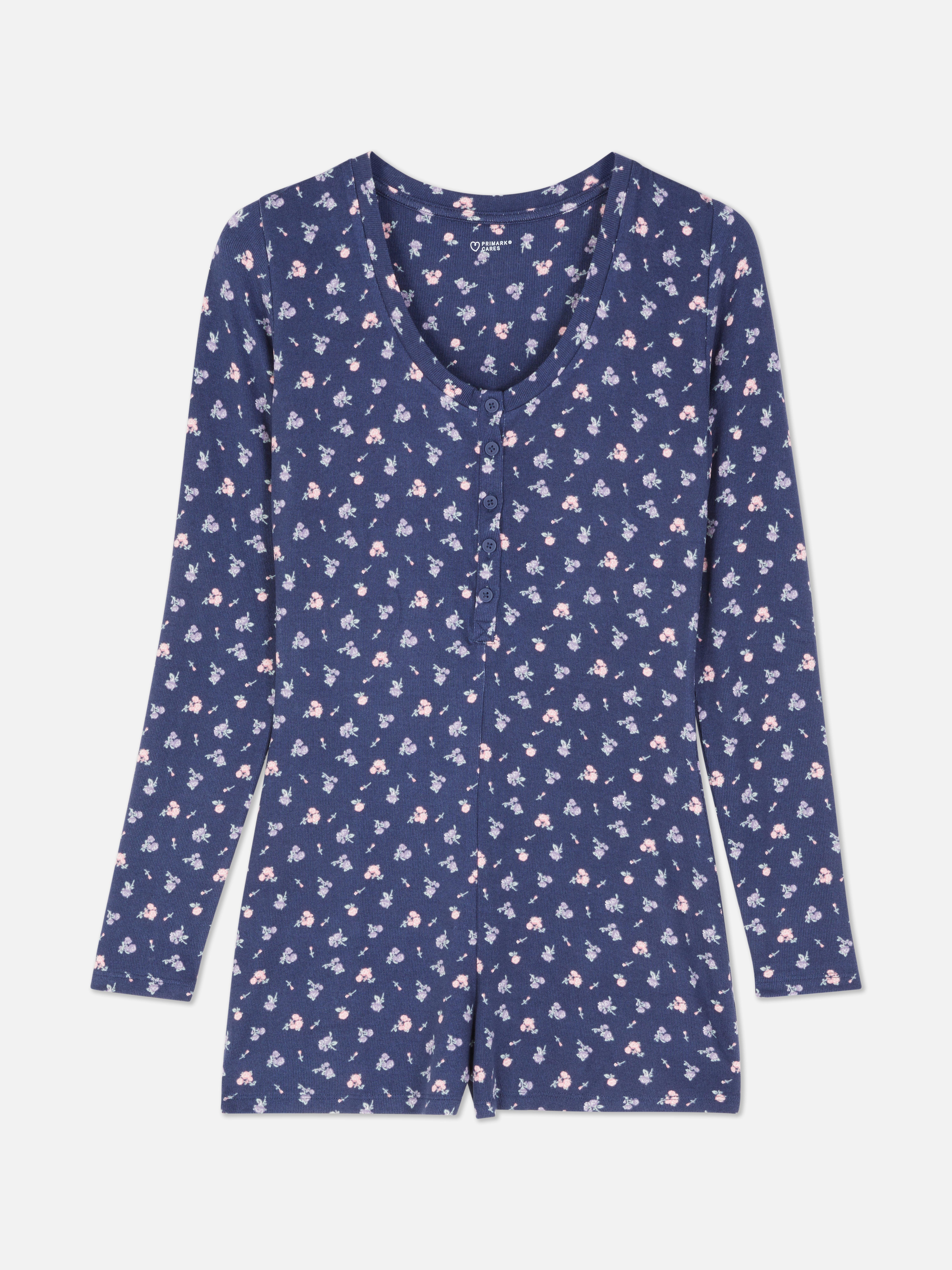Kort strikket pysjamasjumpsuit med blomster En kort pysjamasjumpsuit med V-hals, knappelukking, lange ermer og et heldekkende blomstermønster