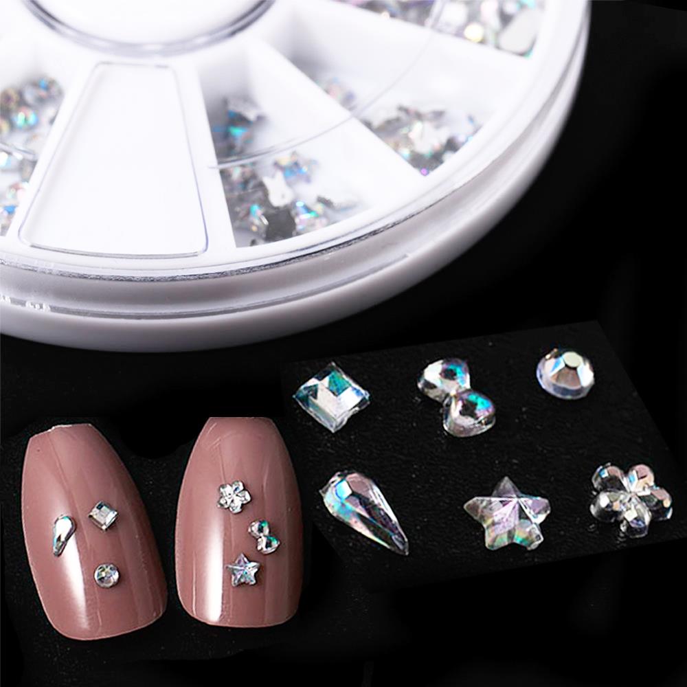 Roue de 6 strass blancs AB de formes variées pour la décoration d'ongles : paillettes, diamant, goutte d'eau, fleur. Accessoire de nail art et bijoux en pierre à faire soi-même.
