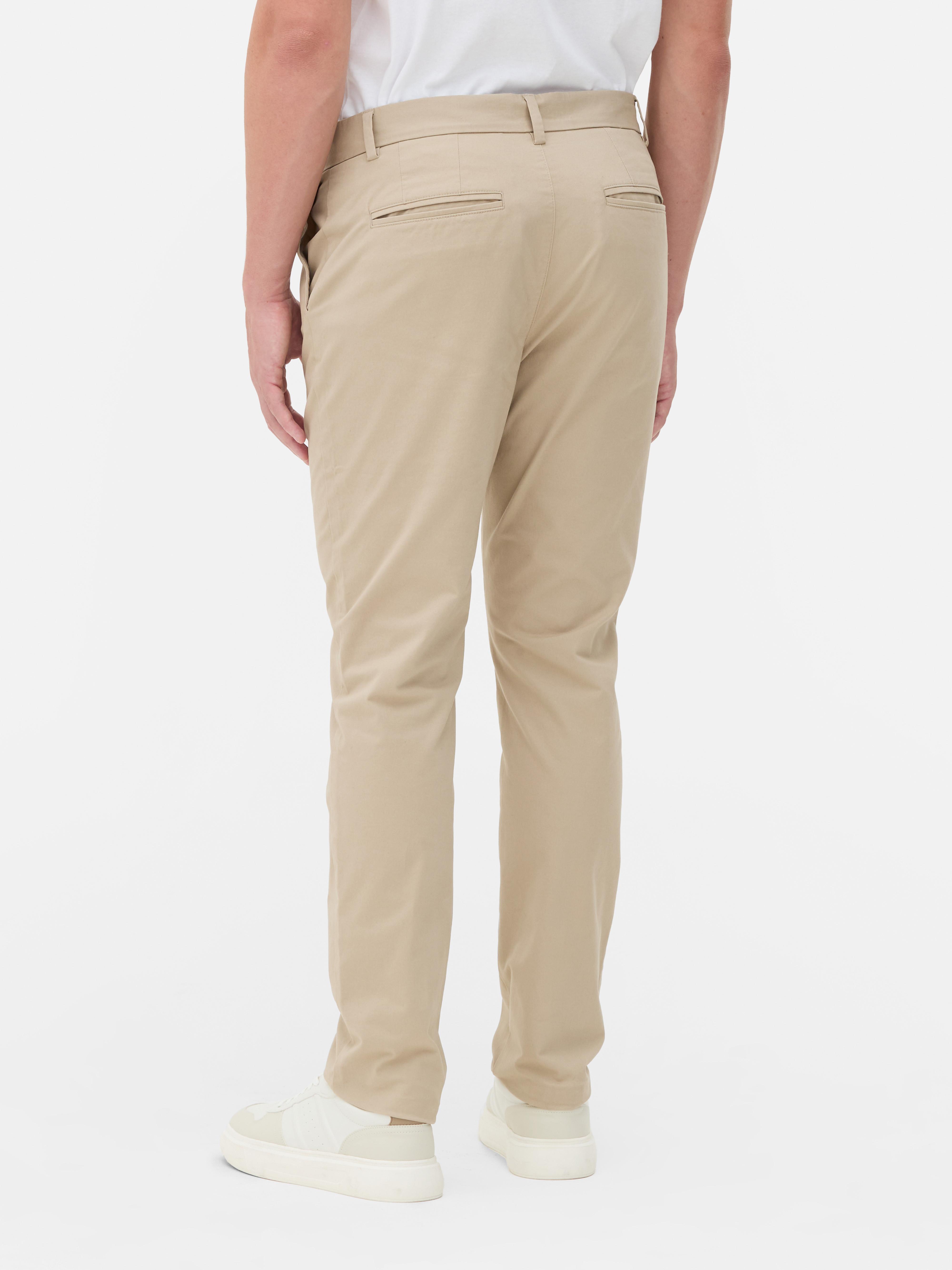 Pantaloni chino elastici, mulați. Pantaloni chino mulați, confecționați în principal din bumbac și cu buzunare laterale.