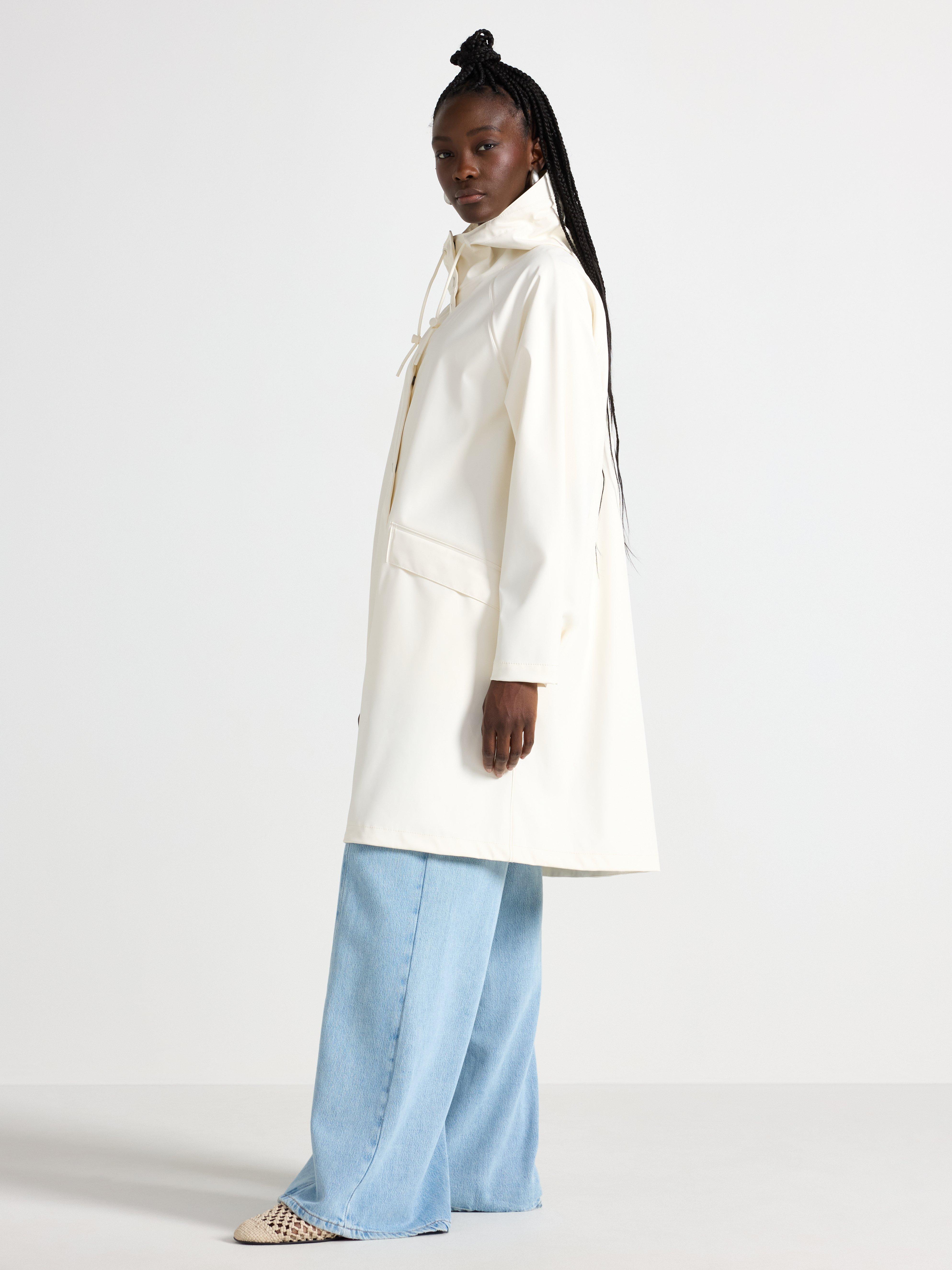 Chaqueta impermeable con capucha color blanco roto.