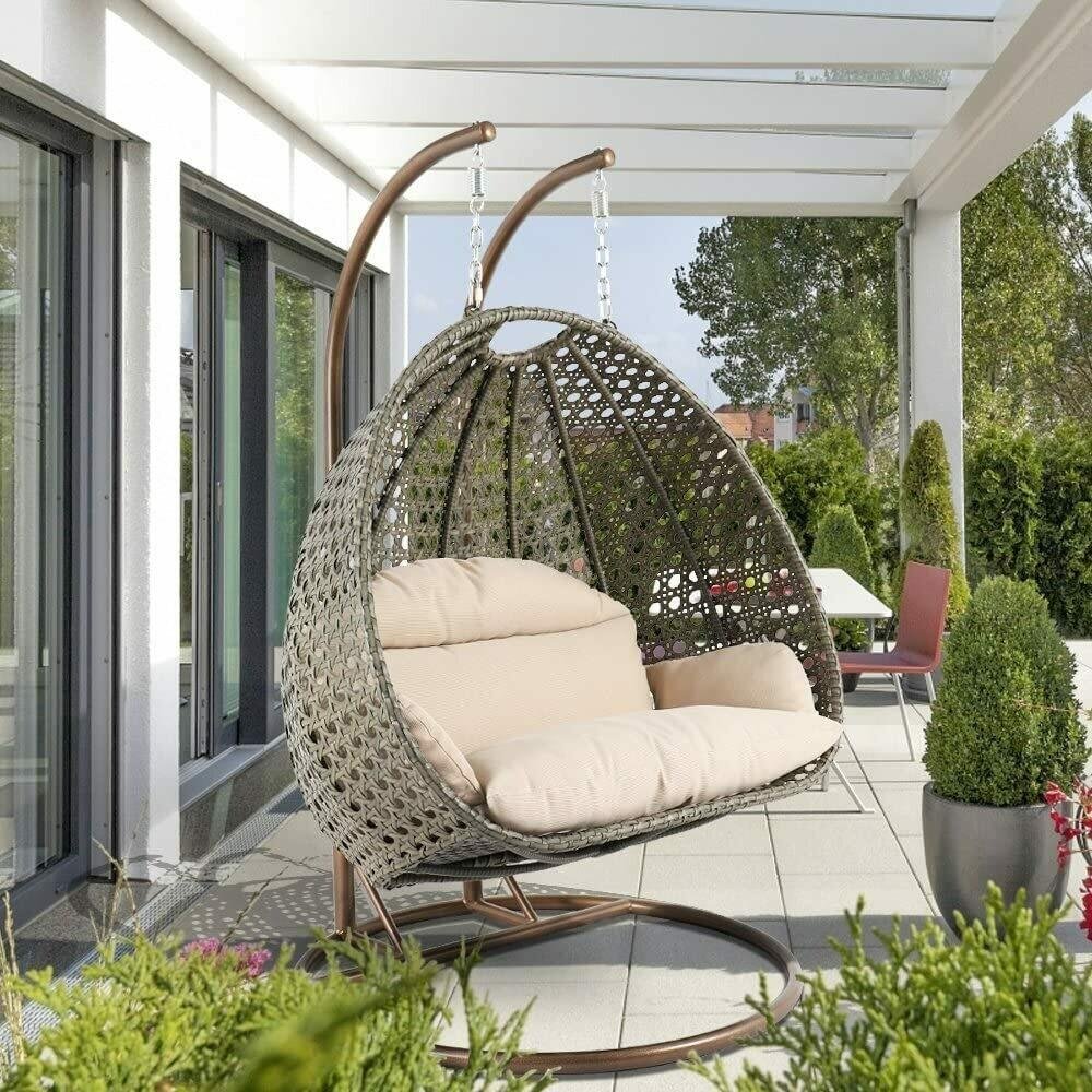 Rotan schommelstoel voor op het terras met standaard en regenhoes.